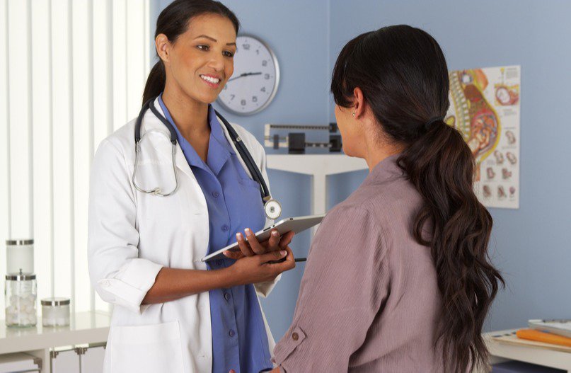 A surgeon explaining breast reduction surgical planning and technique to a patient during a pre-operative consultation.
