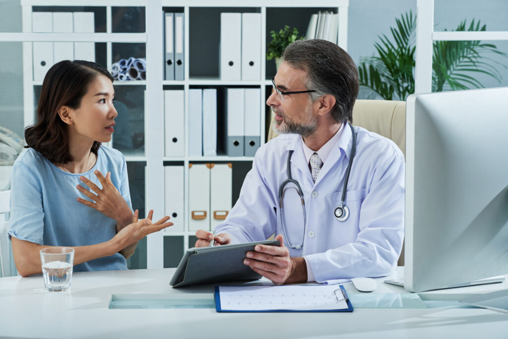 Patient discussing anesthesia options and surgery day details for breast reduction with a doctor during a preoperative consultation.