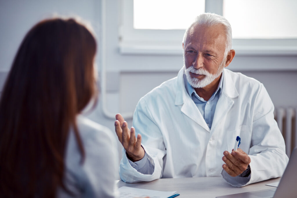 Plastic surgeon discussing long-term results and expected outcomes of breast reduction surgery with a patient during a consultation.