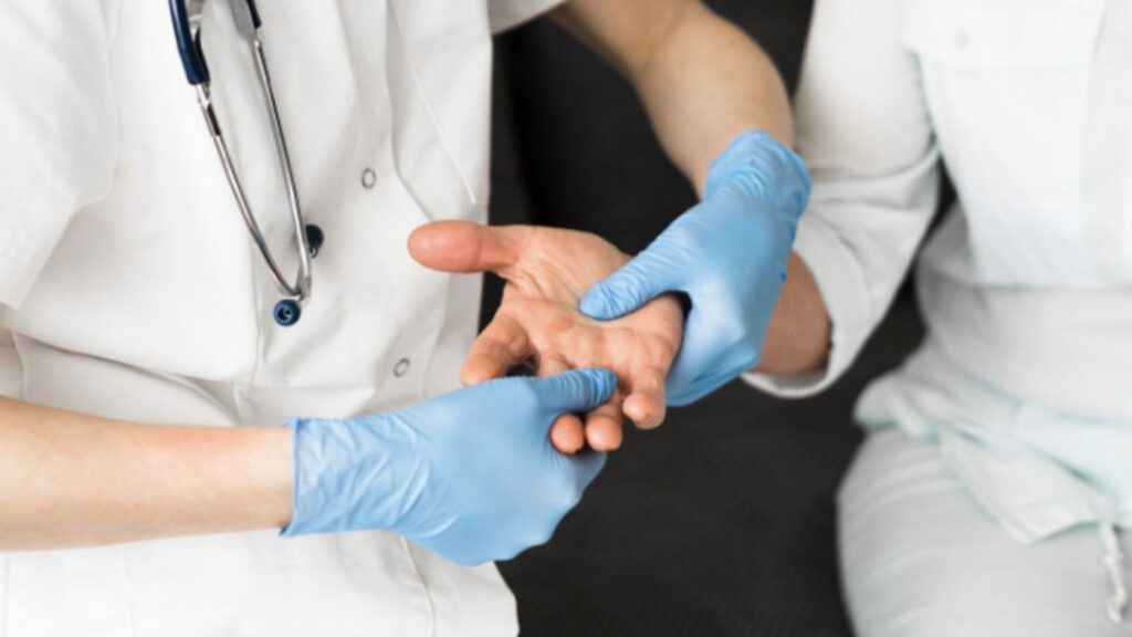 Doctor wearing gloves examining a patient’s hand during microsurgical evaluation
